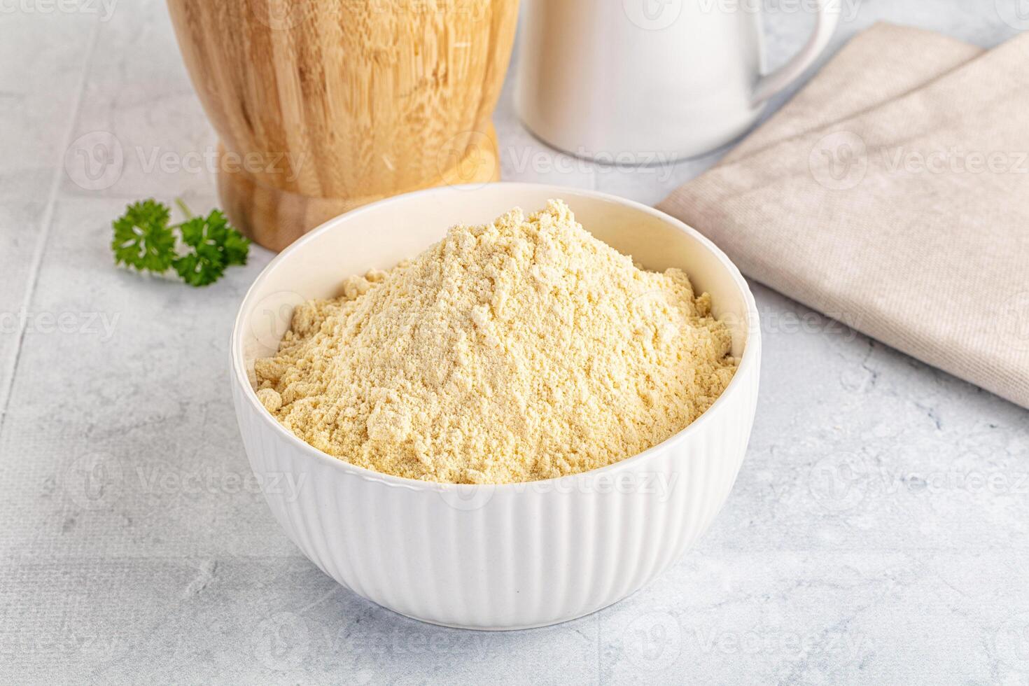 A bowl of flour next to a wooden spoon and a napkin photo