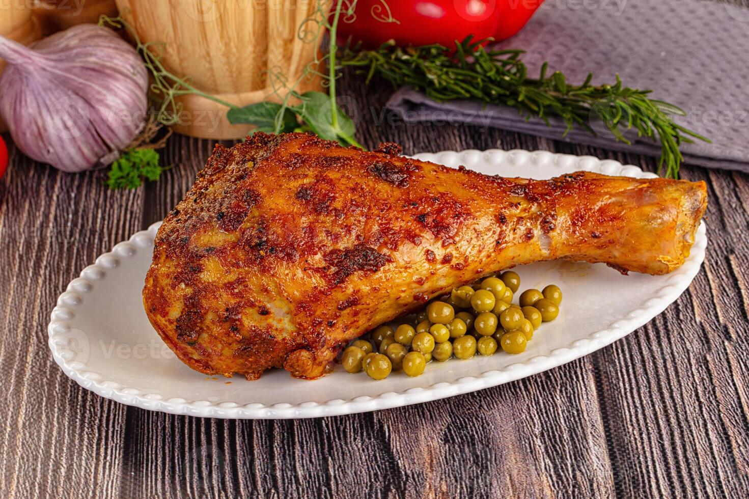 A plate with a chicken leg and peas on it photo