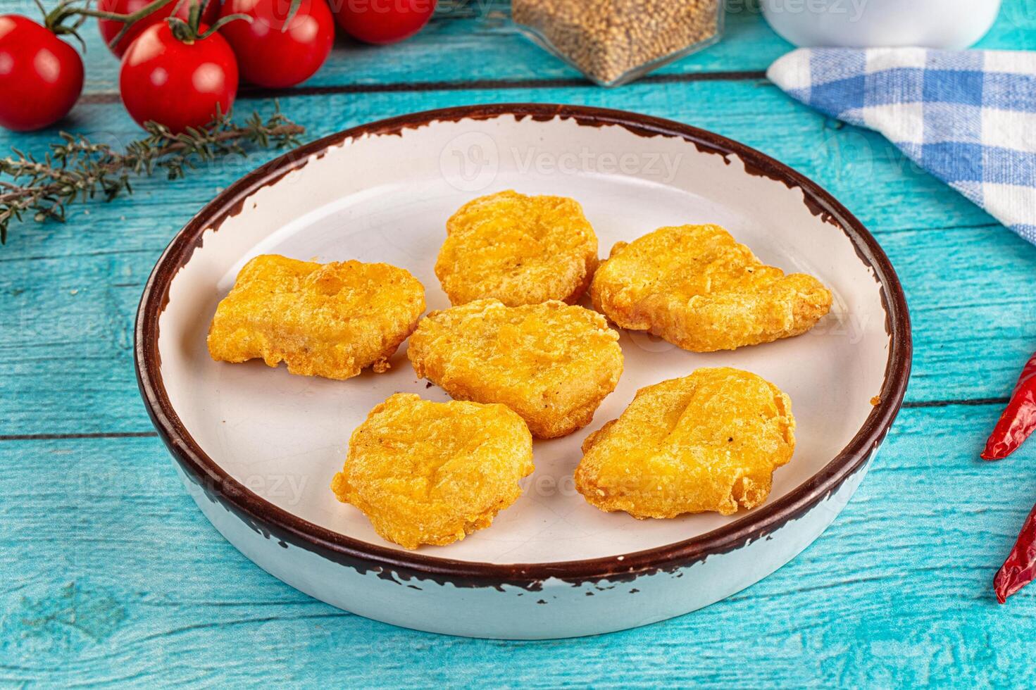A bowl of fried chicken on a table with tomatoes and spices photo