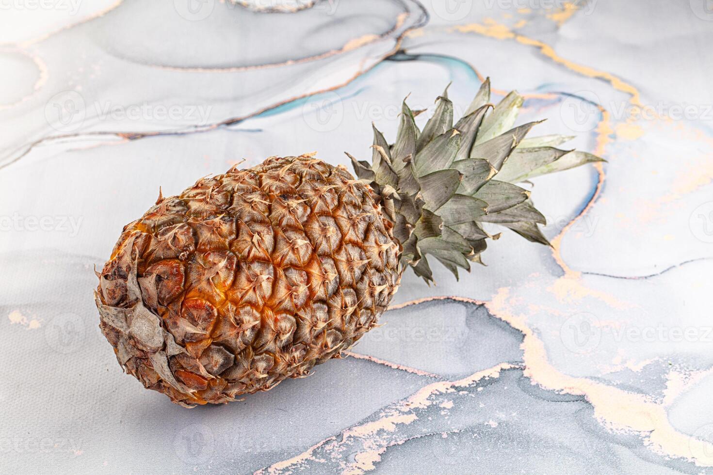 A pineapple is sitting on top of a marble surface photo