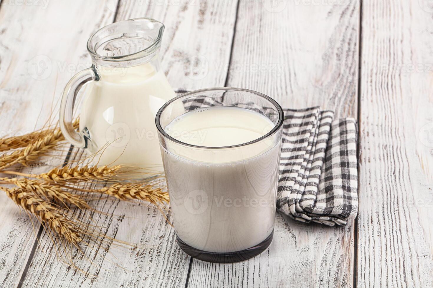 A glass of milk and a jug of milk on a wooden table photo