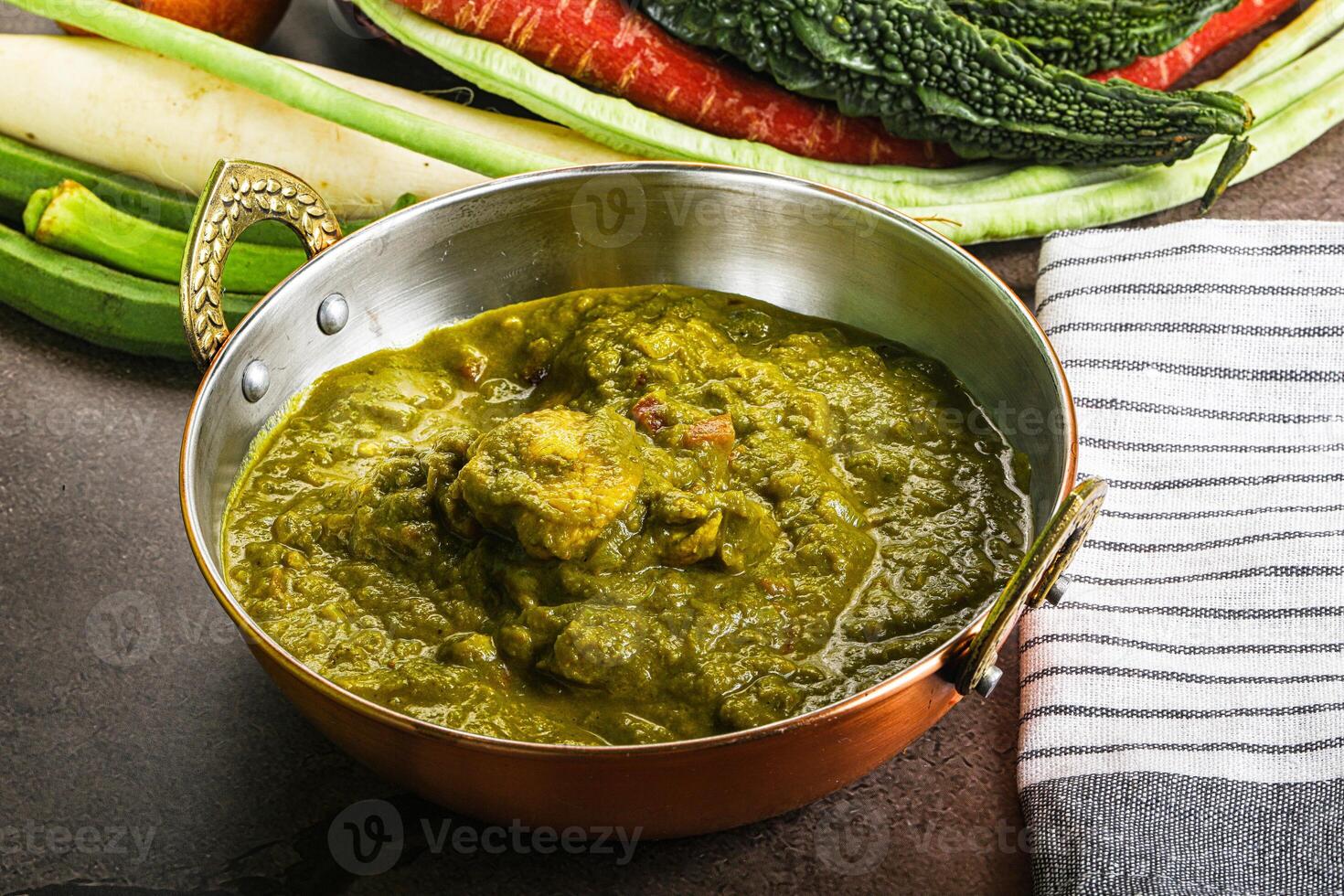A bowl of green food sitting next to a bunch of vegetables photo