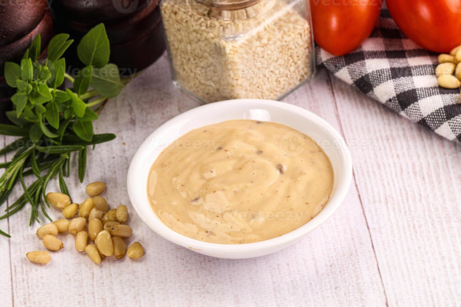 A bowl of dressing next to a bowl of tomatoes and other ingredients photo