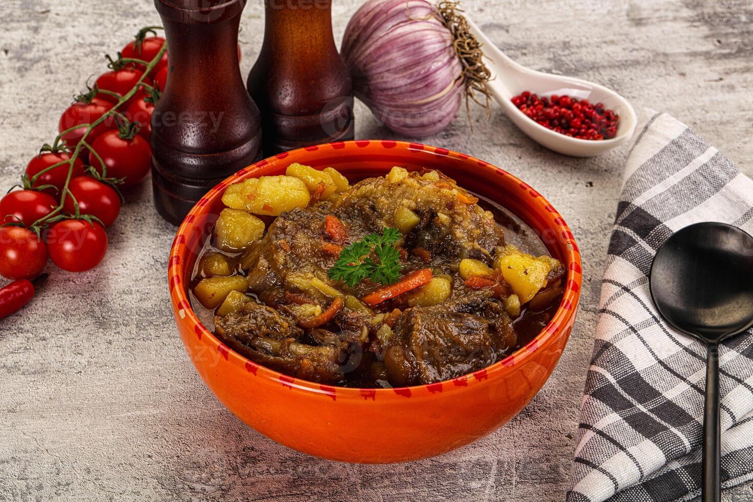 A bowl of stew with vegetables and spices on a table photo