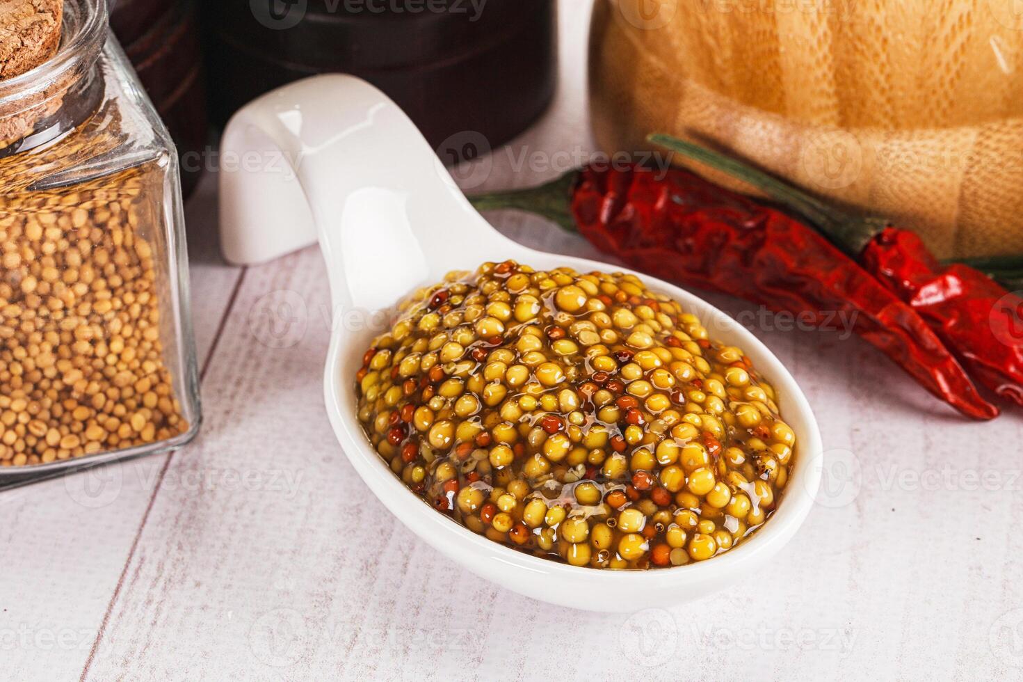 A bowl of mustard seeds and spices on a table photo
