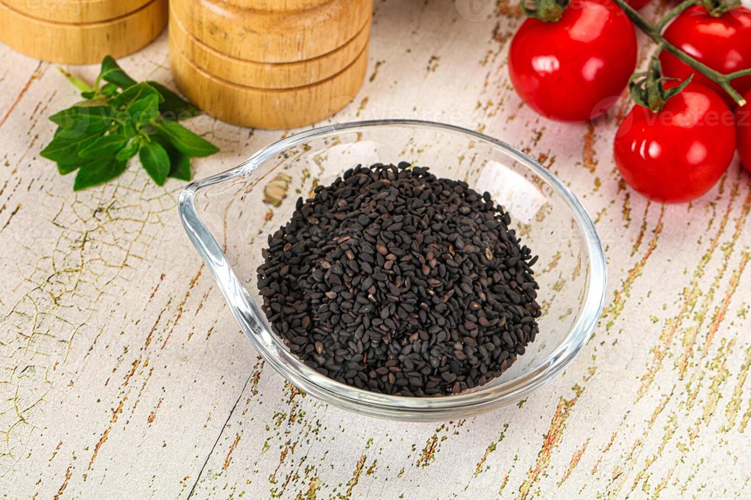 Black cumin seeds in a glass bowl on a wooden table photo