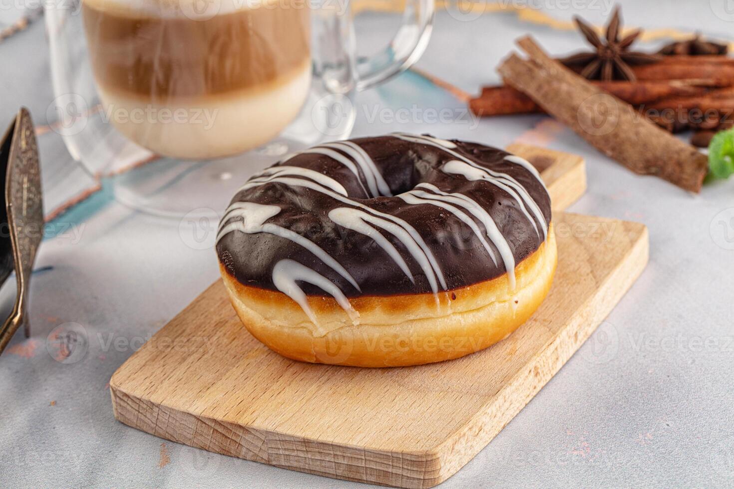 A chocolate donut on a wooden cutting board photo