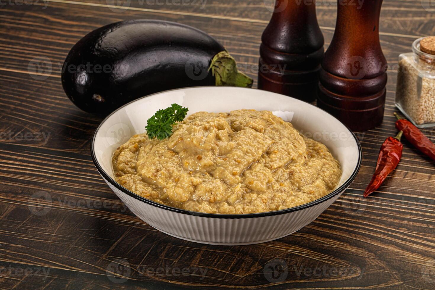 A bowl of hummus with some eggplant and spices photo
