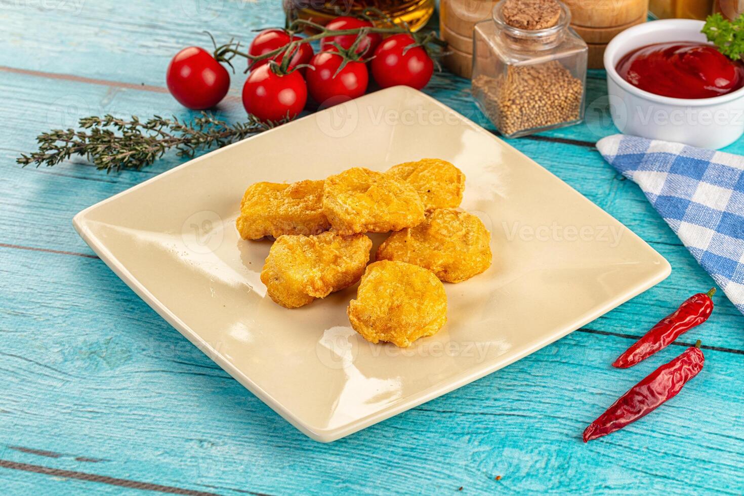 Fried chicken nuggets on a white plate on a blue table photo