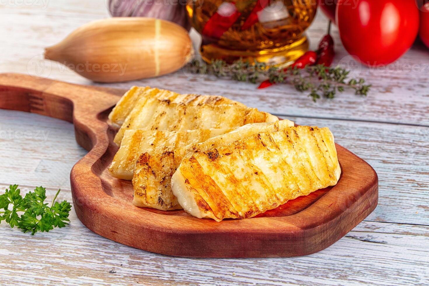 Grilled chicken on wooden cutting board with herbs and vegetables photo