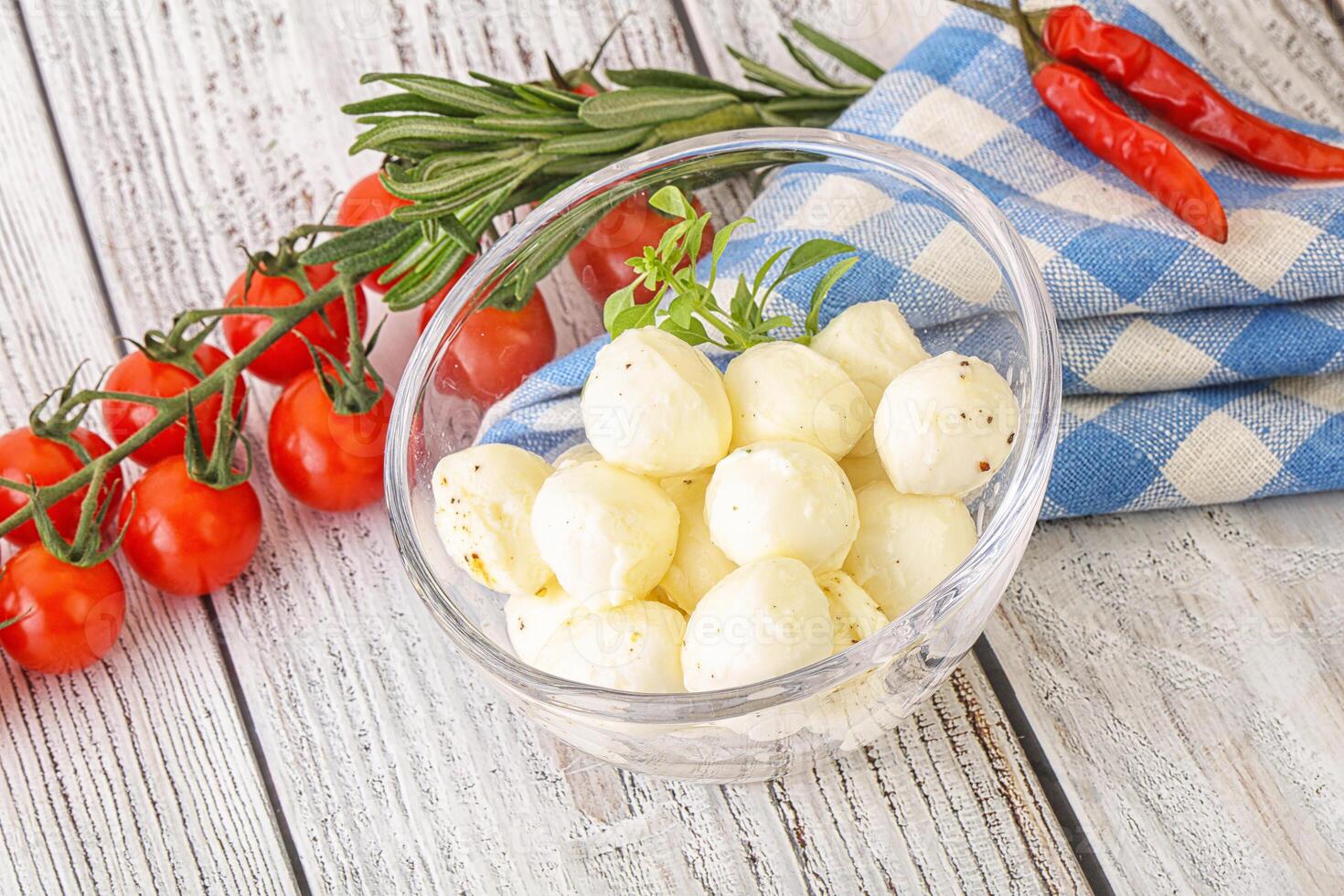 A bowl of cheese and tomatoes on a wooden table photo