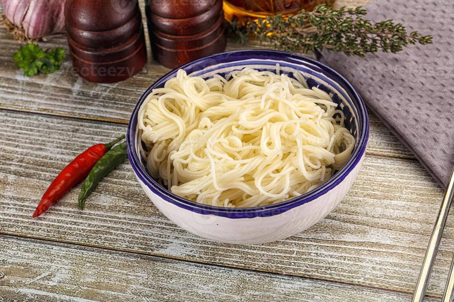A bowl of noodles and chopsticks on a wooden table photo