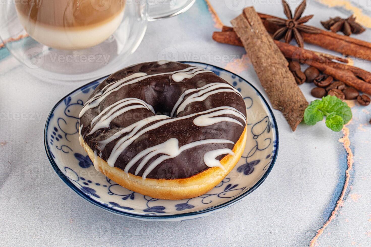 A chocolate donut on a plate next to a cup of coffee photo