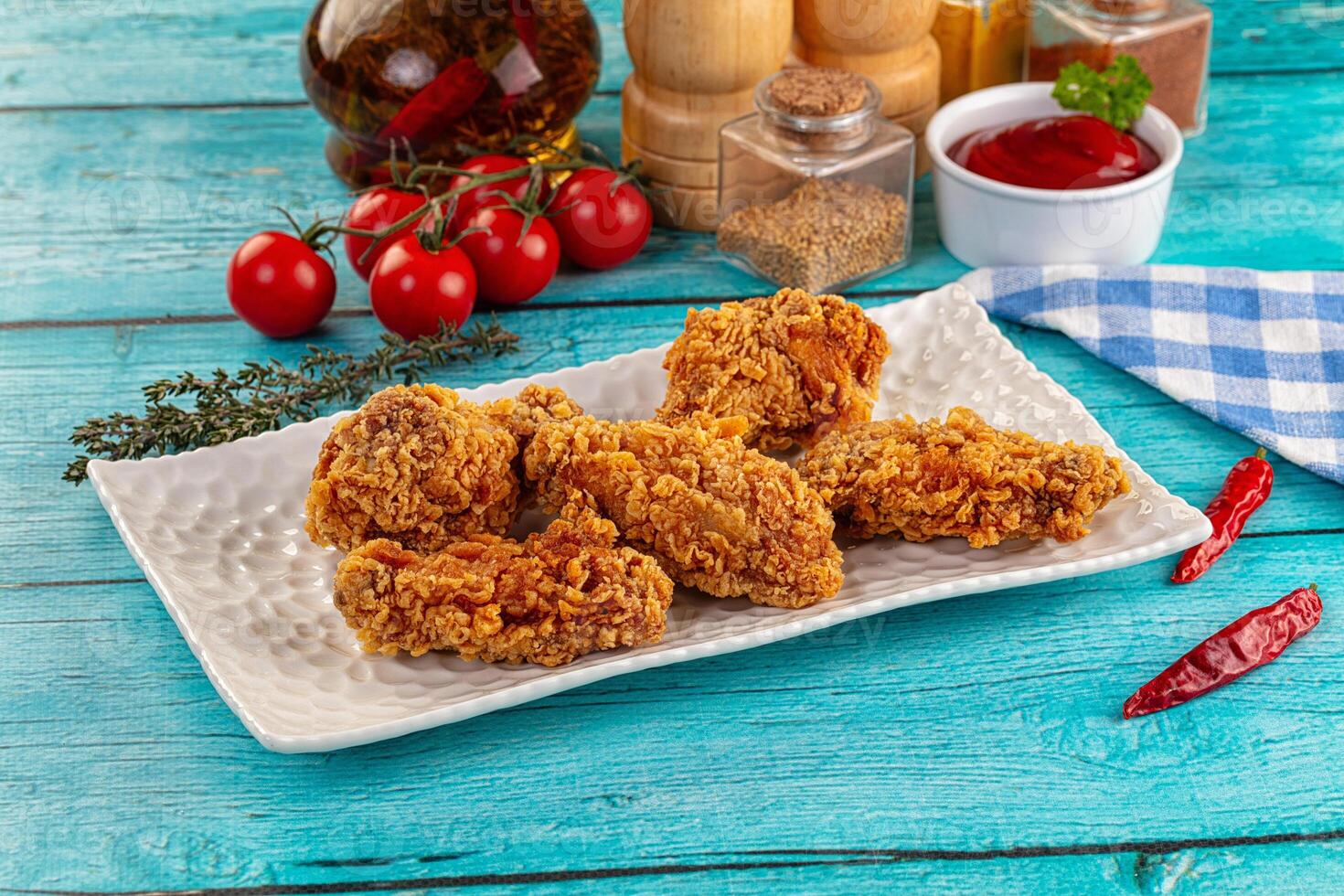 Fried chicken on a white plate with tomatoes and spices photo