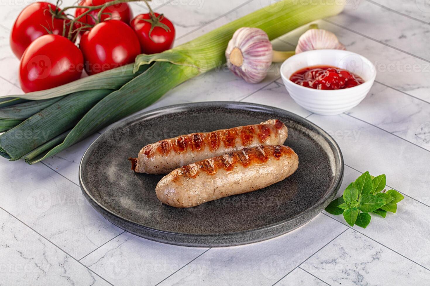 Two sausages on a plate with tomatoes and other ingredients photo