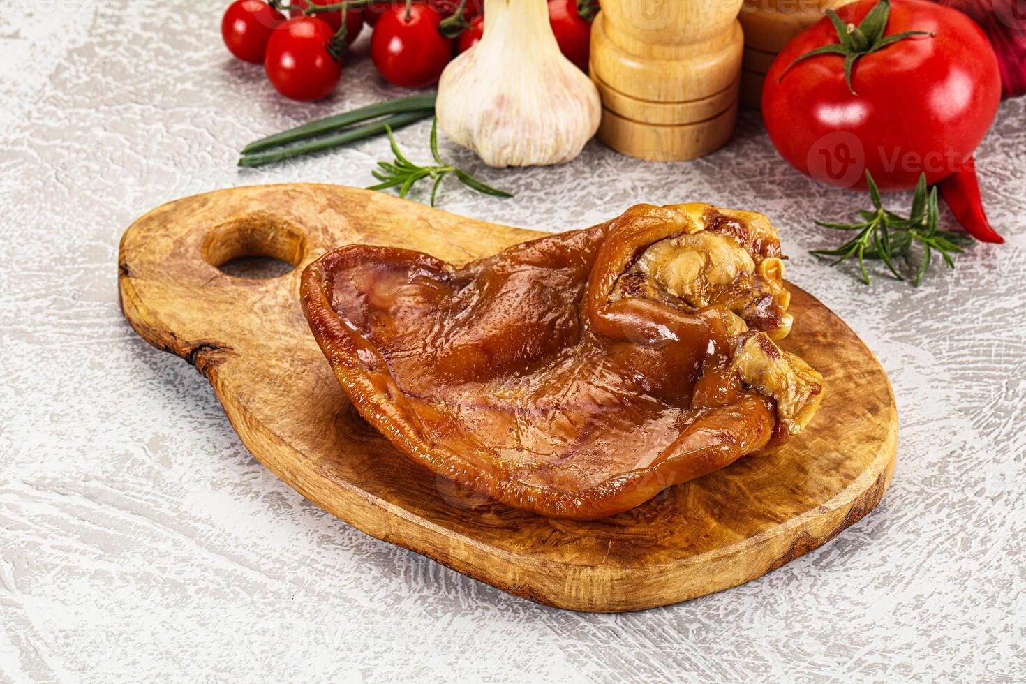 A piece of meat on a wooden cutting board with vegetables photo