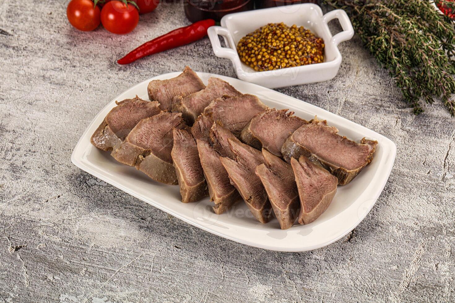 A plate of meat with spices and vegetables on a table photo