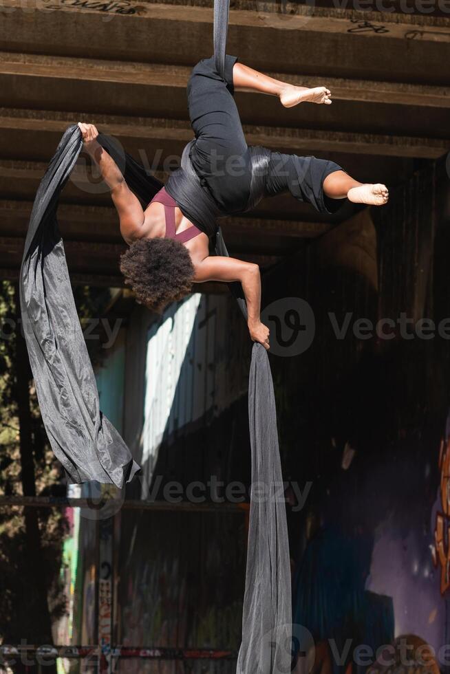 Slim woman doing aerial yoga in city photo