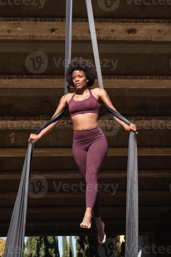 Slim woman doing yoga with aerial silks in city photo