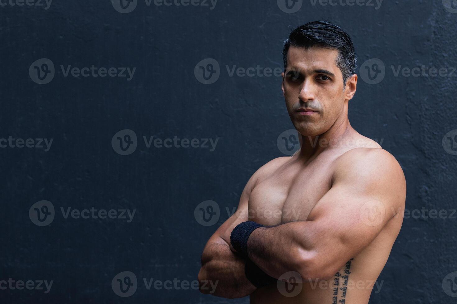 Positive shirtless Hispanic sportsman near wall photo