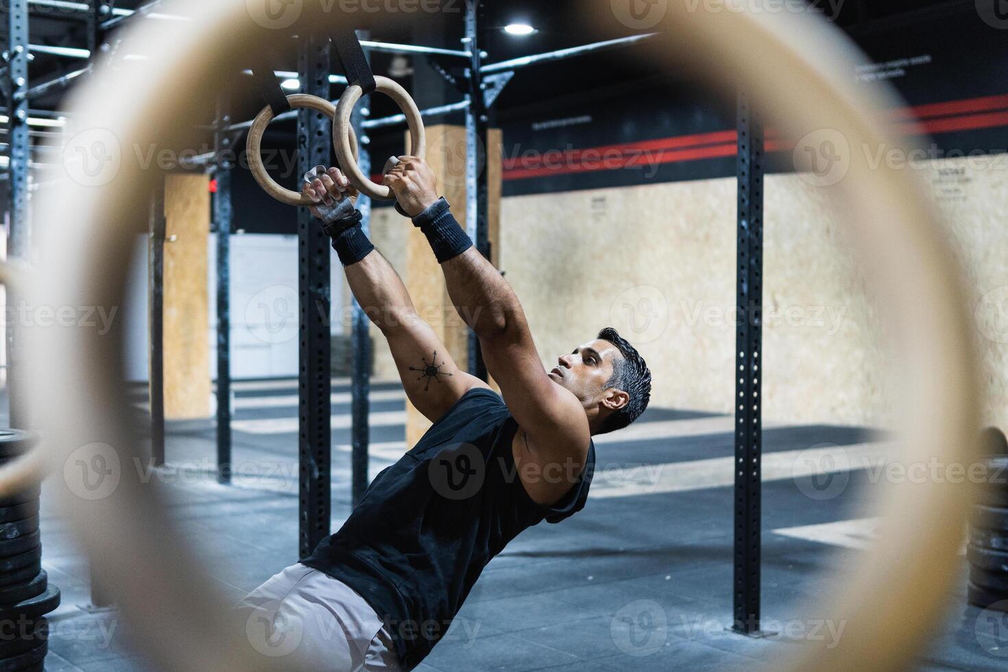 Hispanic sportsman exercising with gymnastic rings photo