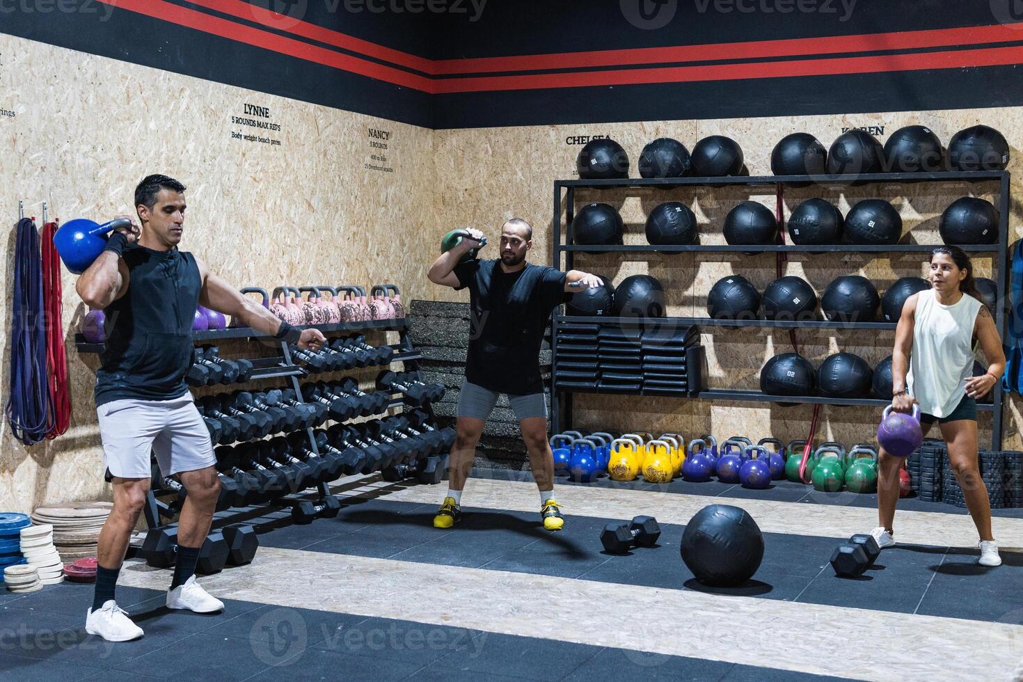 Hispanic sportspeople lifting kettlebells in gym photo