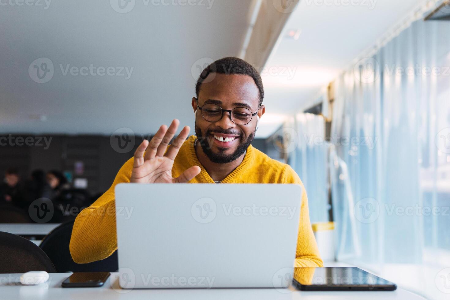 Smiling black man calling on laptop in workspace photo