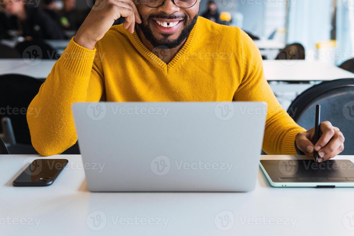 Anonymous smiling black man working on laptop with tablet photo