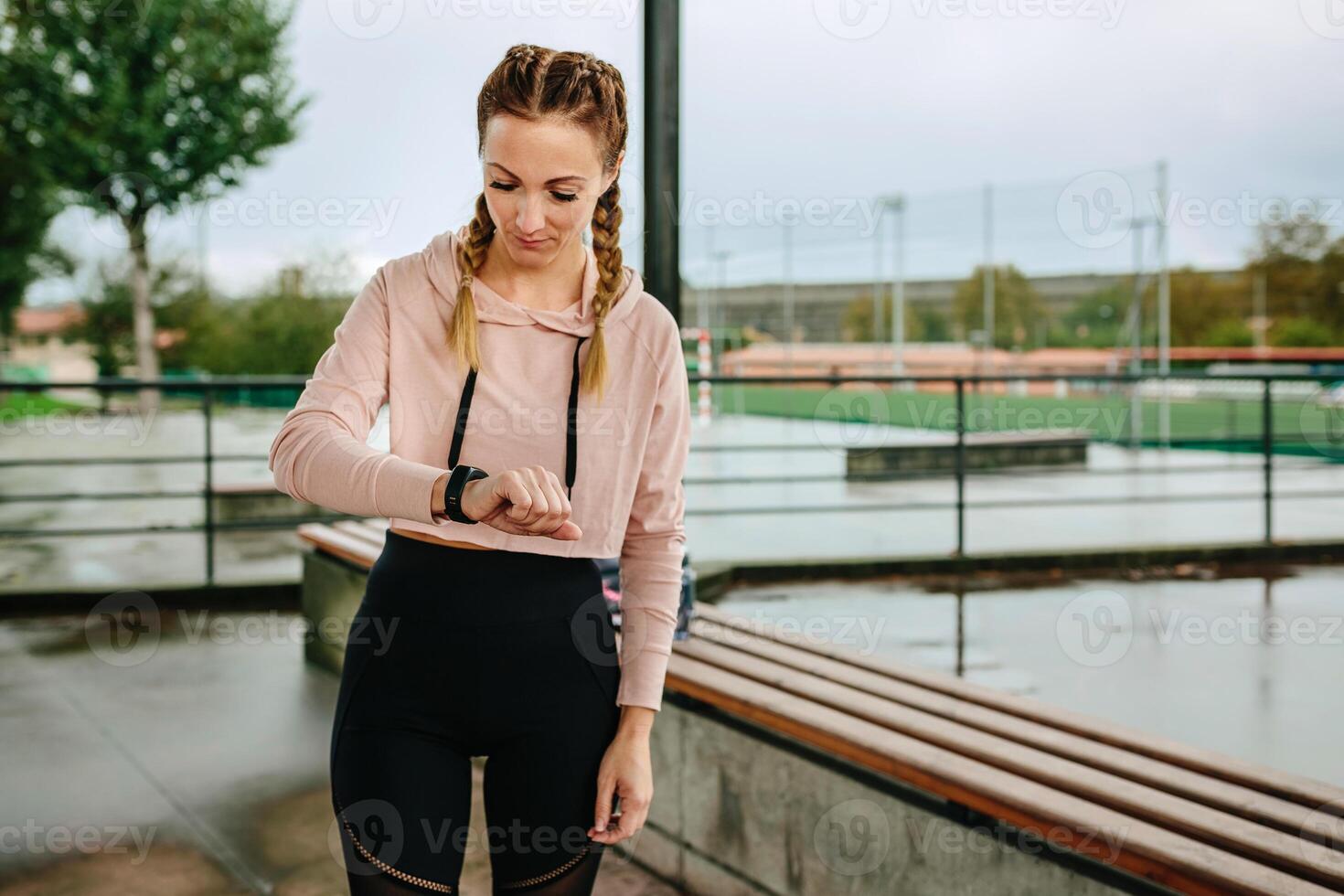 Young sportswoman looking activity bracelet photo