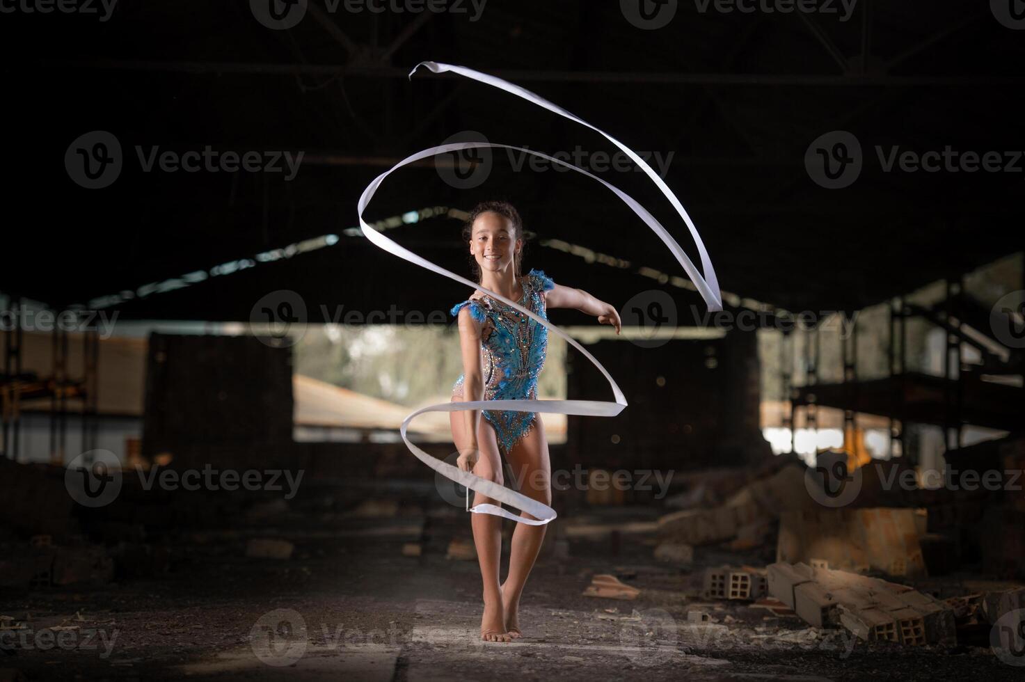 Young girl performing rhythmic gymnastics exercises outdoors photo