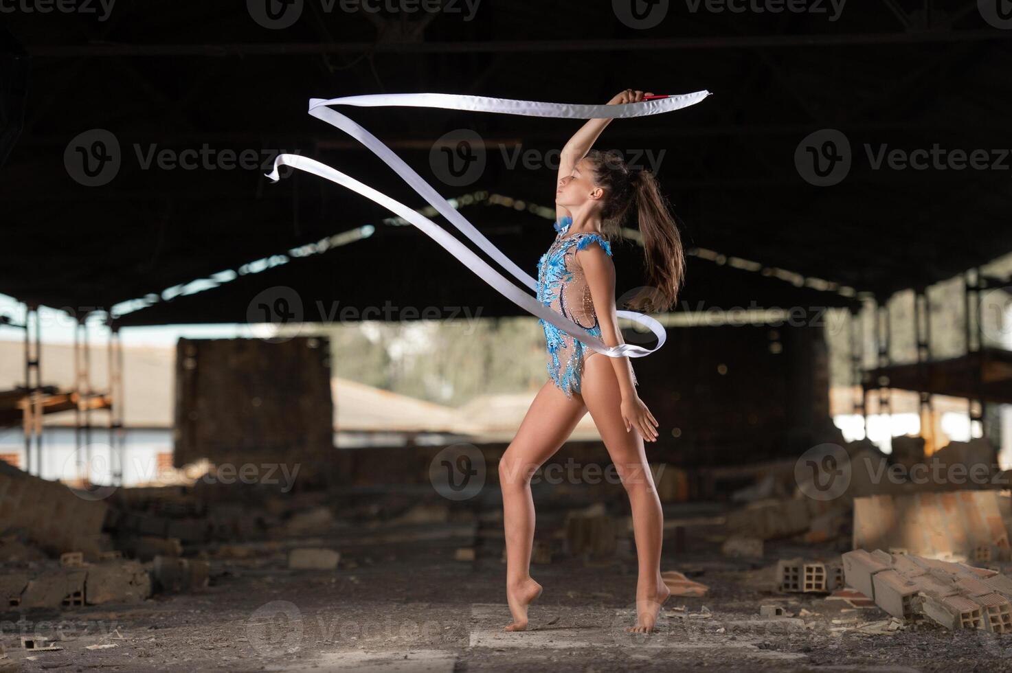 Young girl performing rhythmic gymnastics exercises outdoors photo