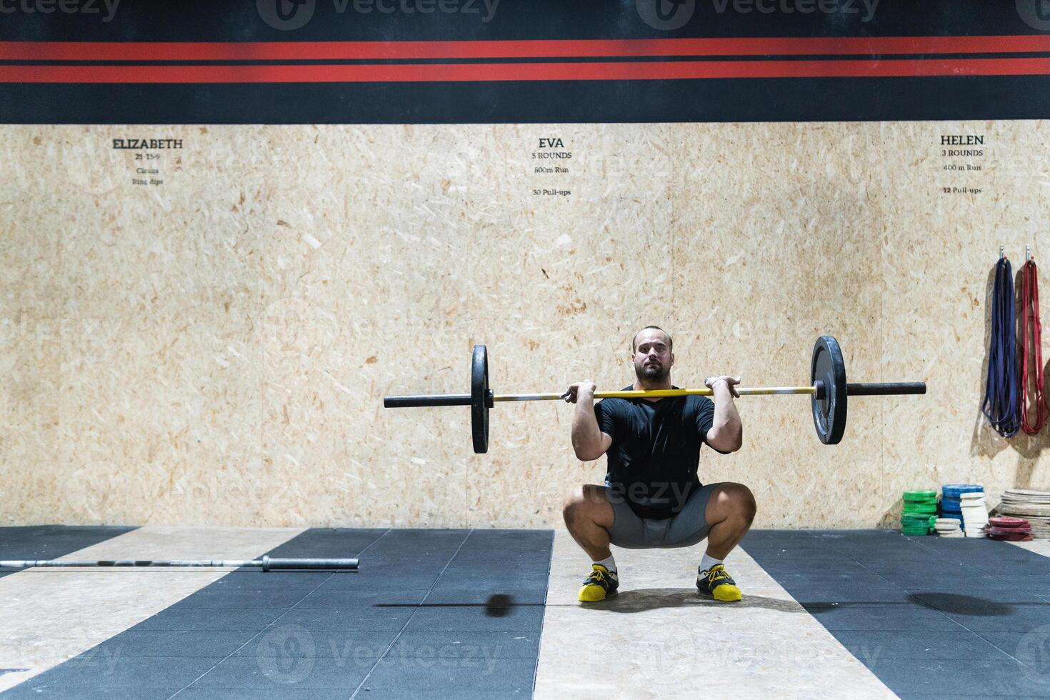 Muscular sportsman lifting heavy barbell photo