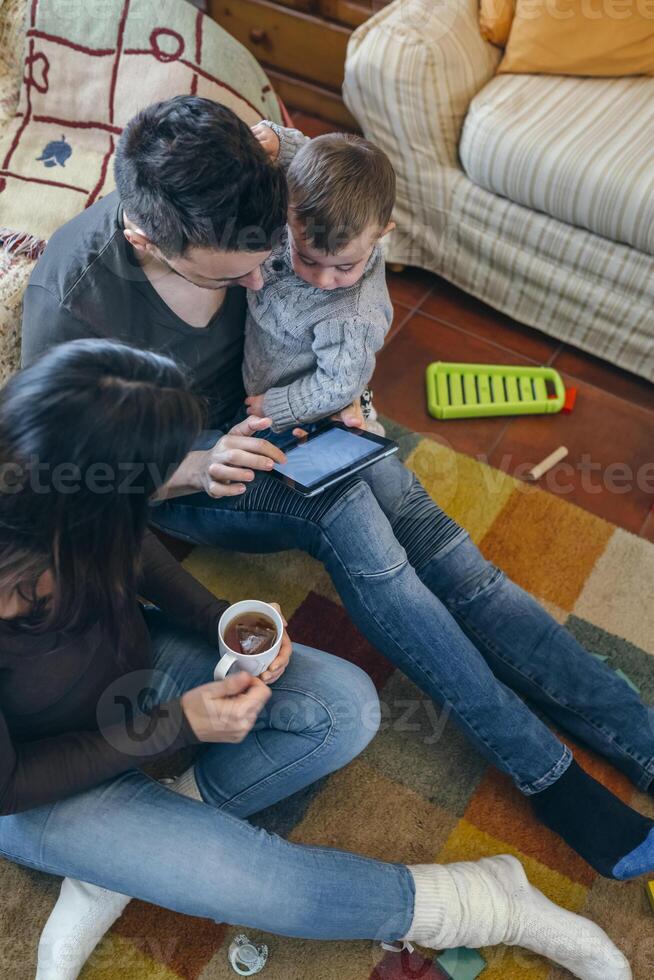 Family with child and pregnant mother looking tablet photo