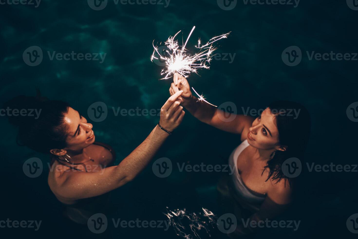 Cheerful friends burning sparkles near pool photo