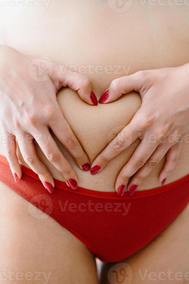 Naked woman showing heart with fingers on body photo