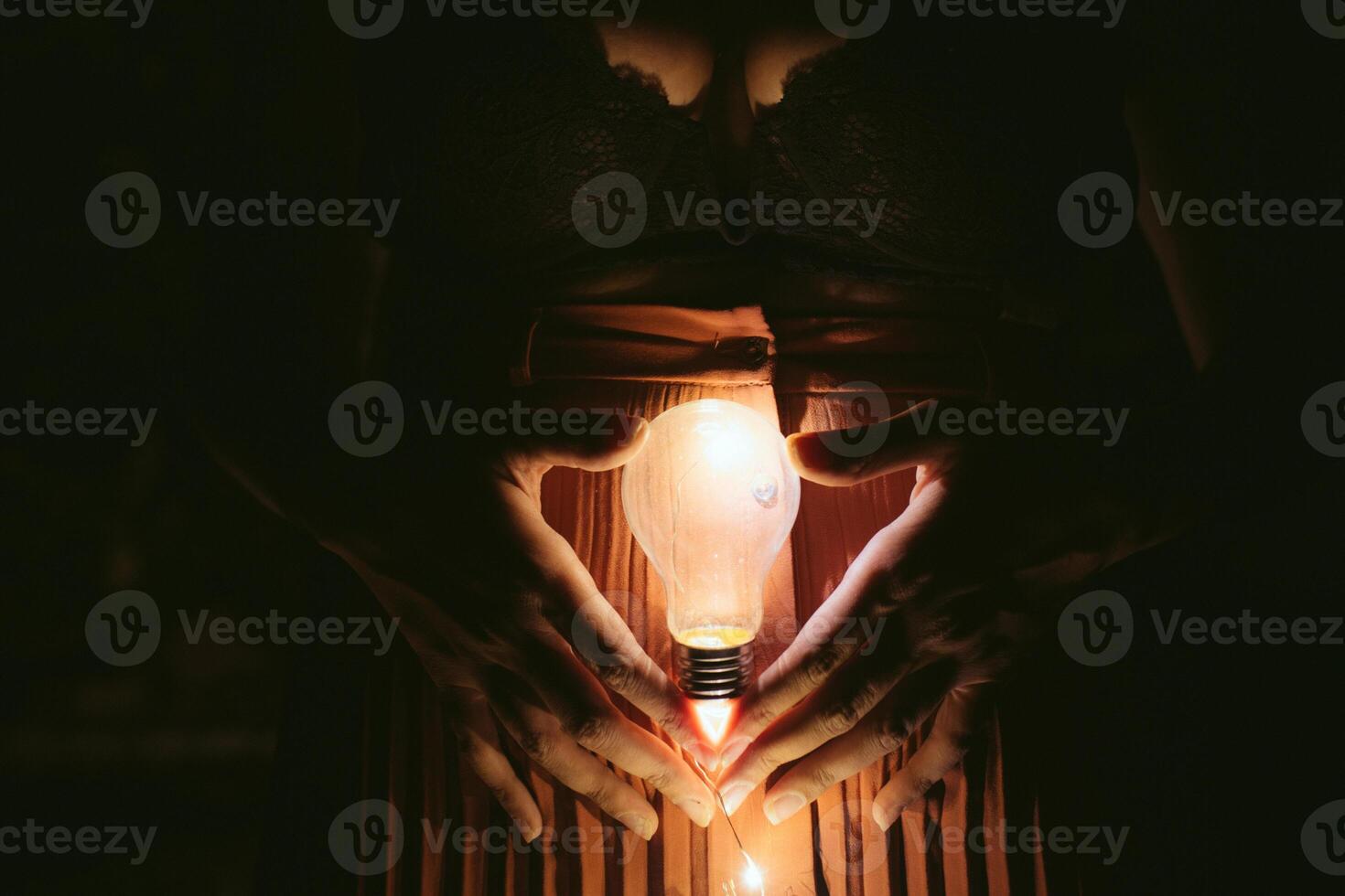 Faceless female with lightbulb in darkness photo