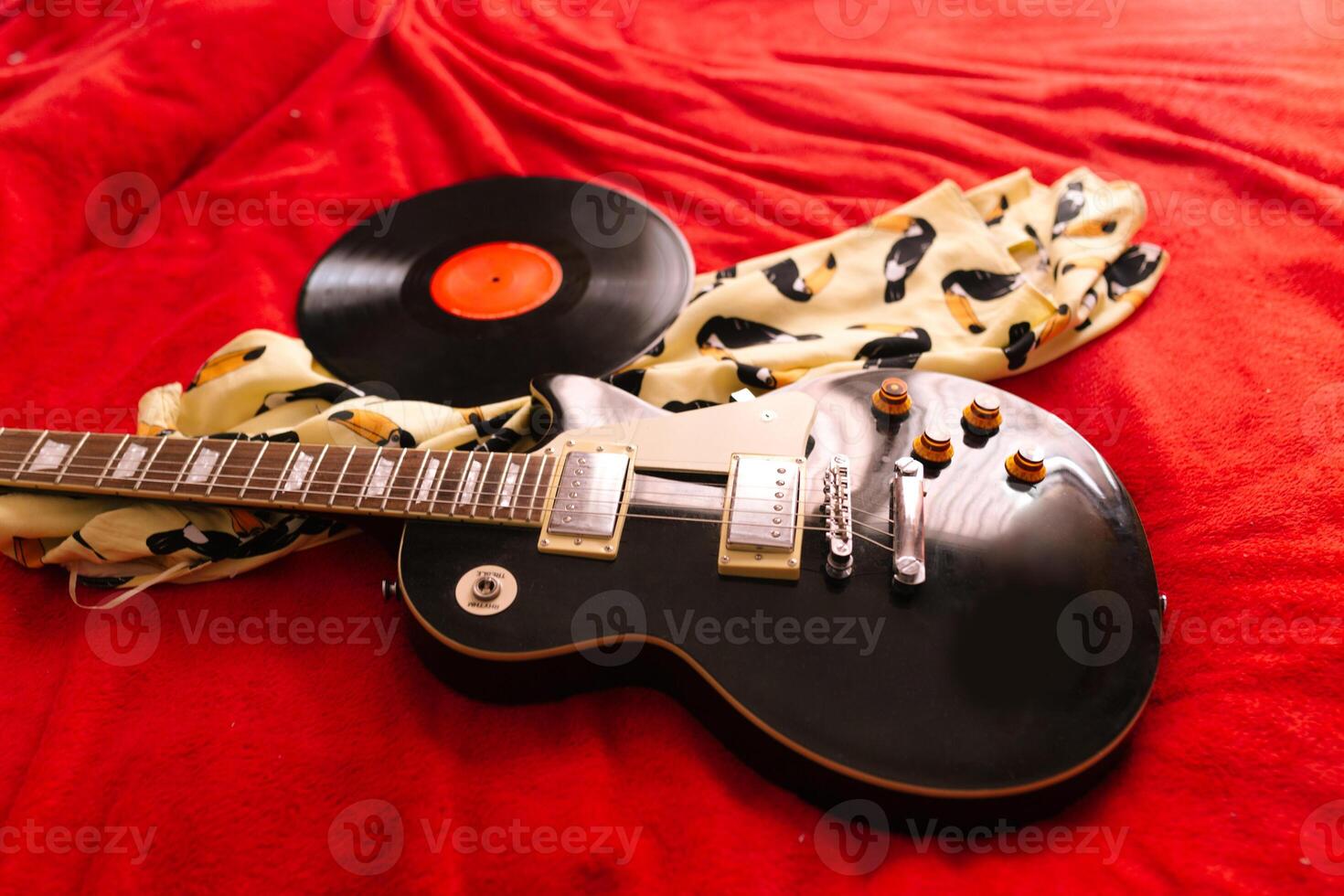 Vinyl record and electric guitar on bed photo