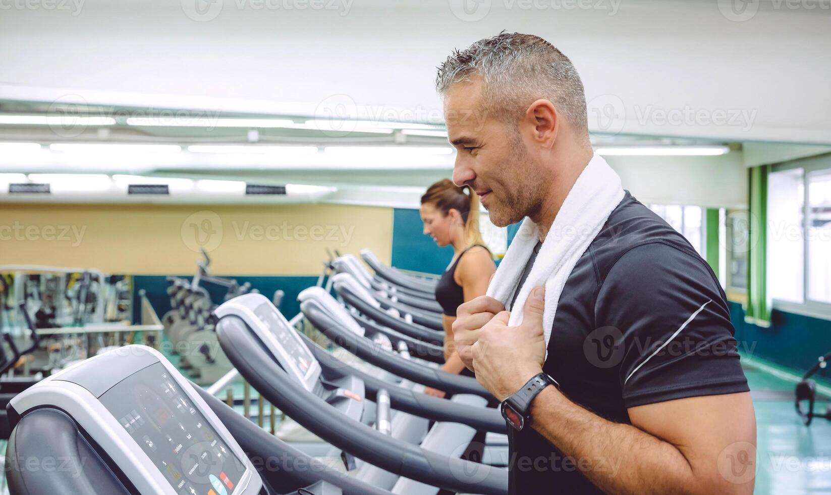 Man with towel in neck training over treadmill photo