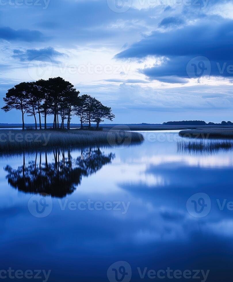 Blue sky and water with trees reflected in the water photo