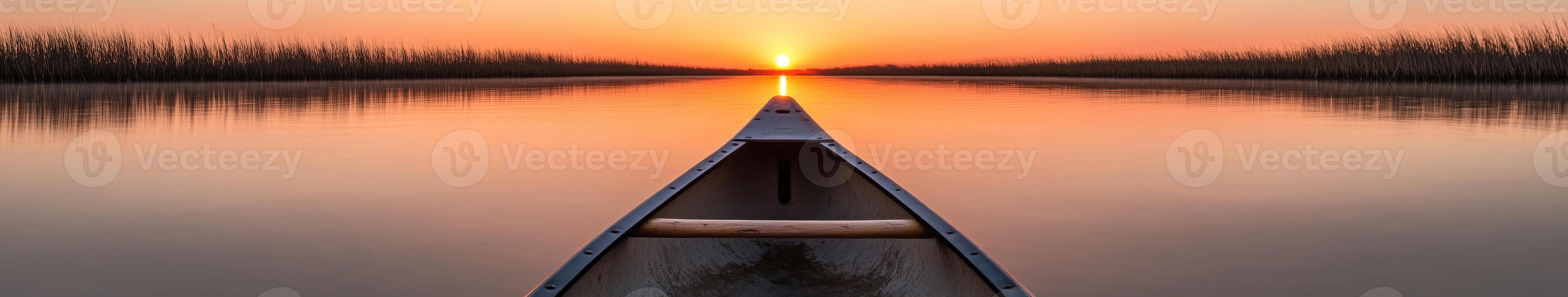 A canoe is seen in the middle of a lake at sunset photo
