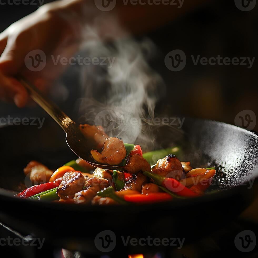 stir-fried chicken with vegetables in a wok on a dark background. Hand stir the food. Selective focus. photo