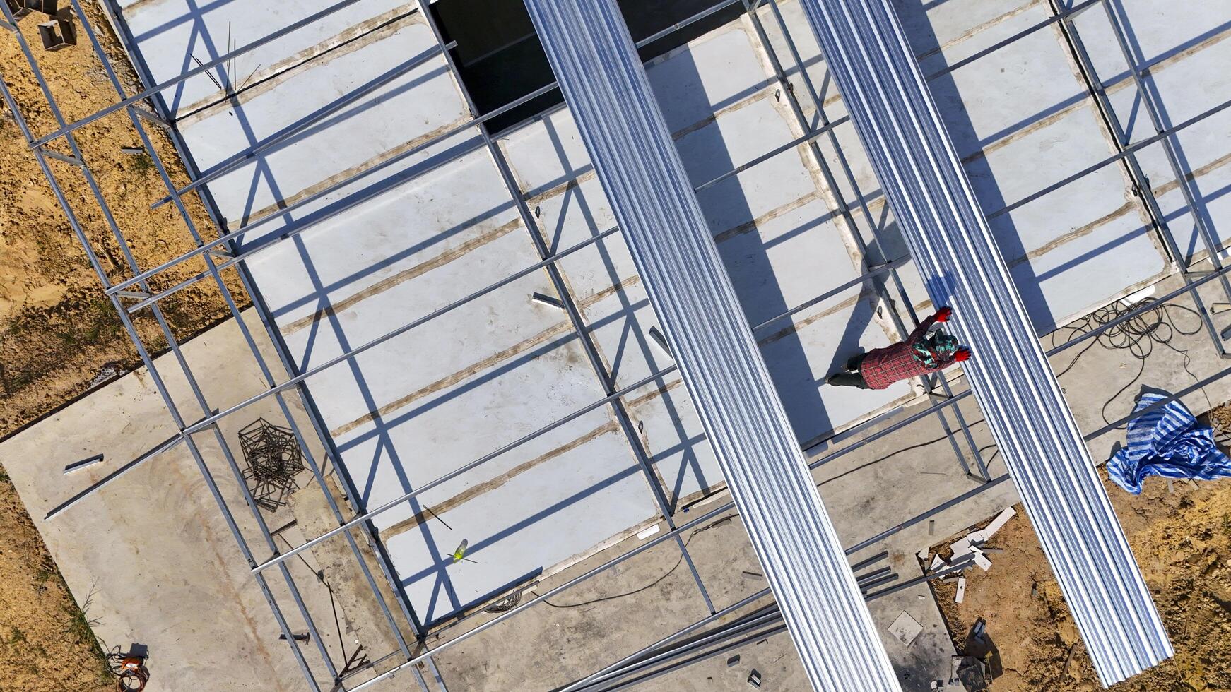 Aerial view of construction workers installing roofing panels on a building, surrounded by tools and materials, showcasing teamwork, precision, and the construction process in progress photo