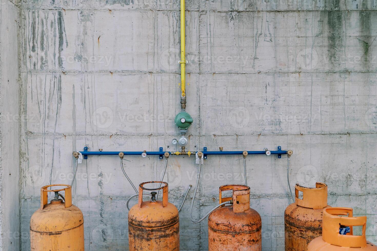 Gas cylinders connected to pipes on a concrete wall photo