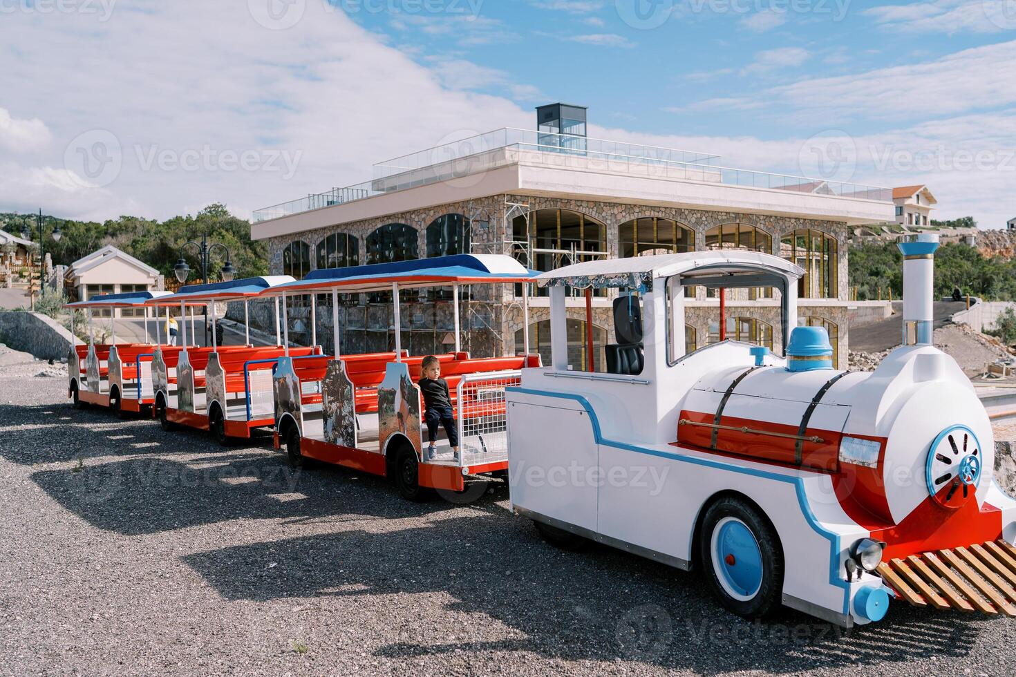 Little girl sits in the carriage of a colorful train on the playground photo