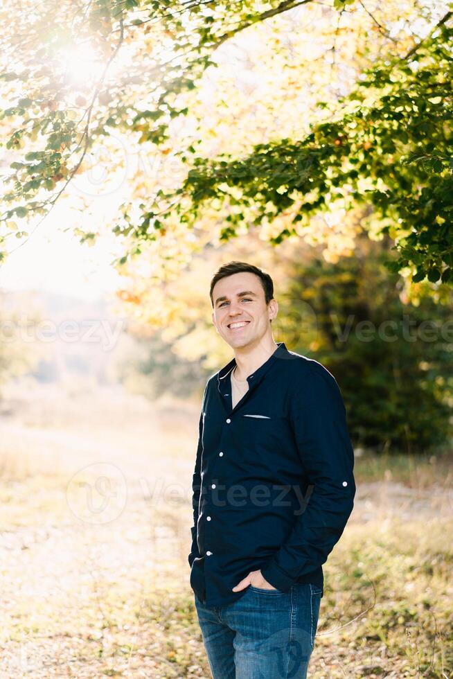 Smiling man standing on the lawn under a tree photo