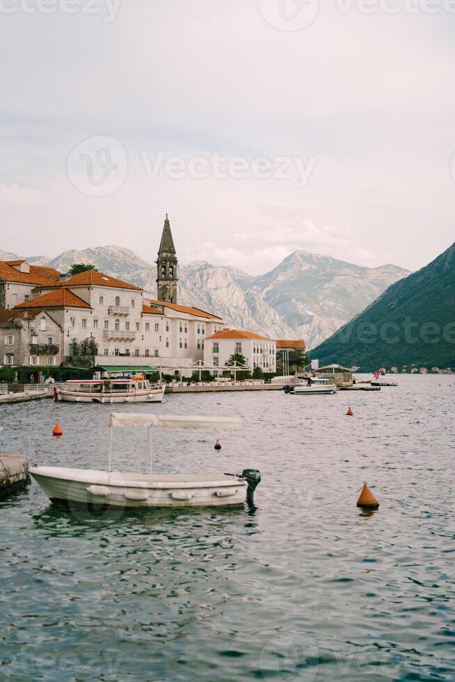 Excursion boats are moored off the coast of Perast with old houses and the bell tower of the Church of St. Nicholas. Montenegro photo