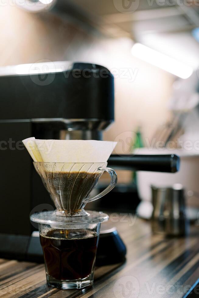 Coffee being filtered in a pour over coffee machine on the table photo