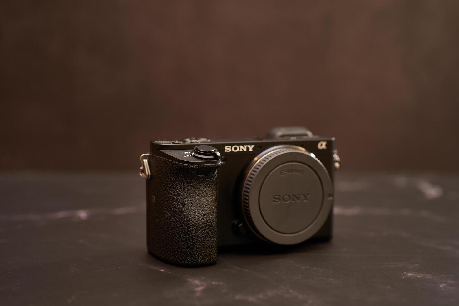 USA, Arizona - March 10, 2025. Sony A6300 digital mirrorless camera with a lens cap stands on a black marble table photo