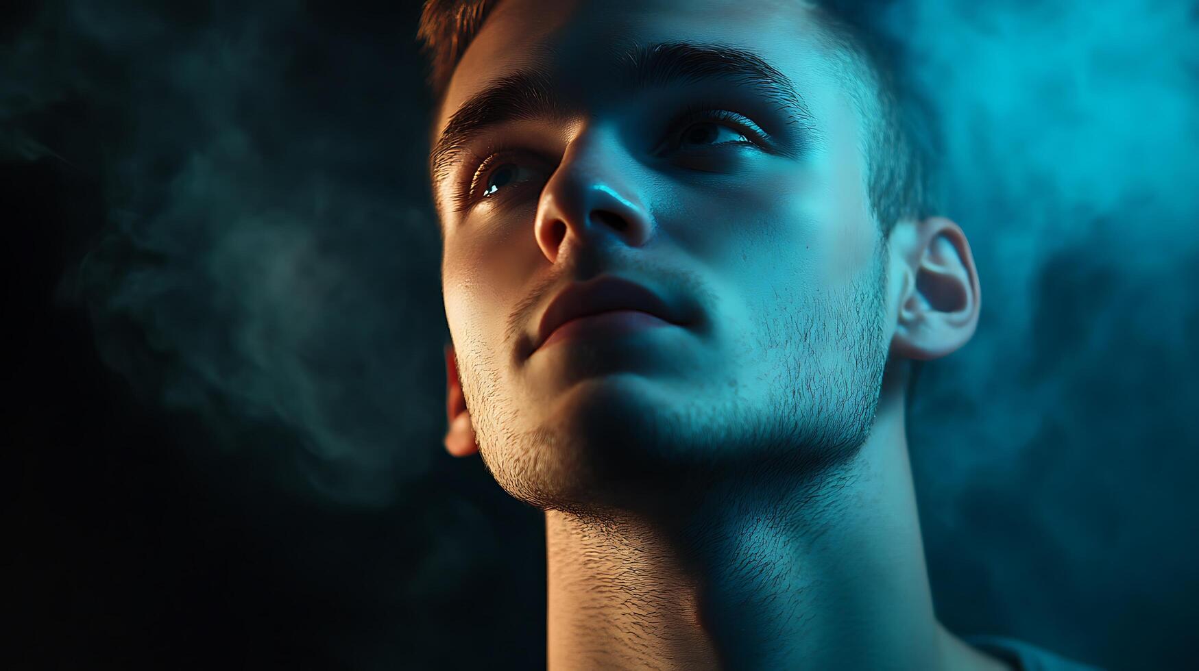 Focused gaze of a young man bathed in blue light face angled upward expression thoughtful against a smokey backdrop photo