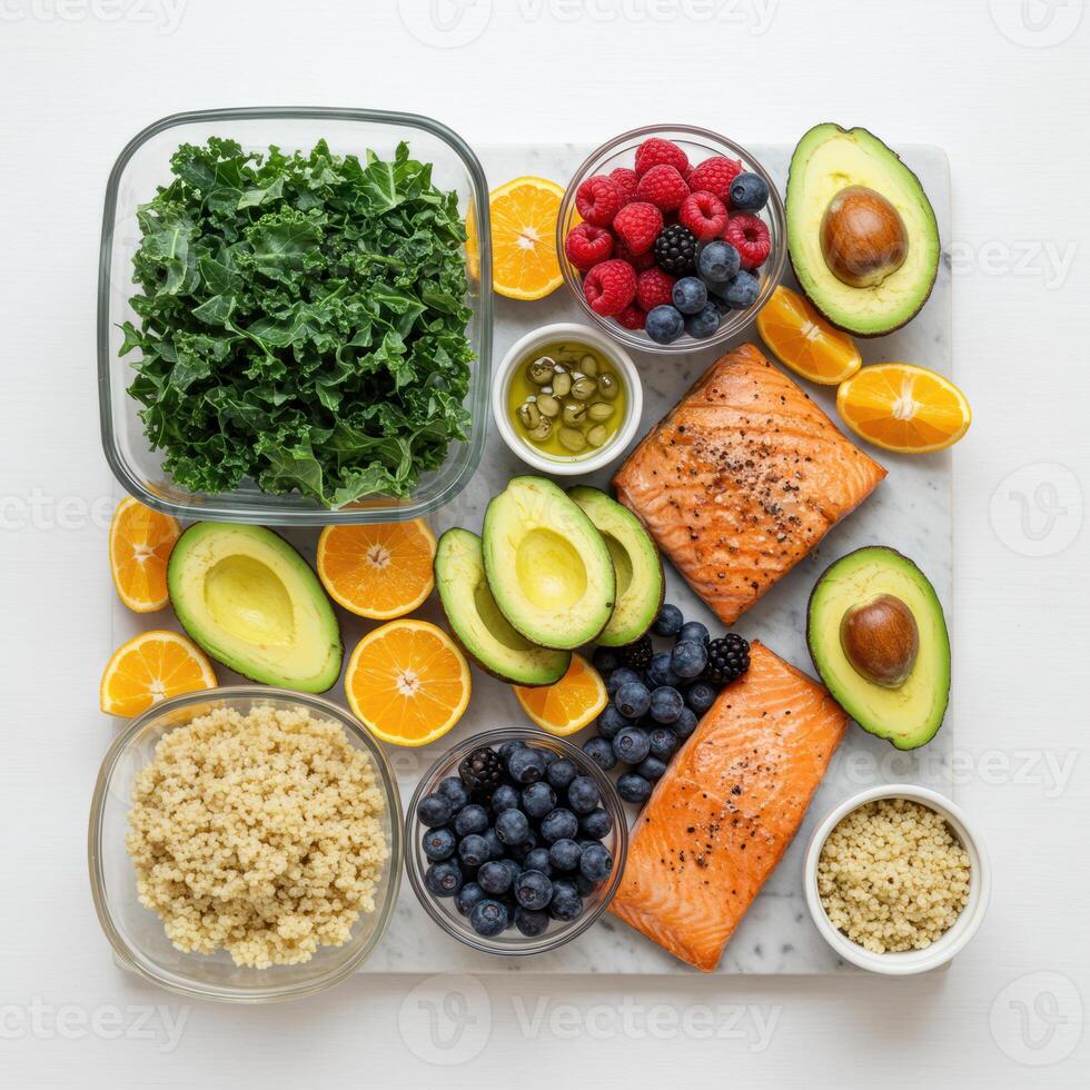 Overhead view of a nutritious meal prep featuring salmon, avocado, quinoa, kale, and fresh fruit. photo